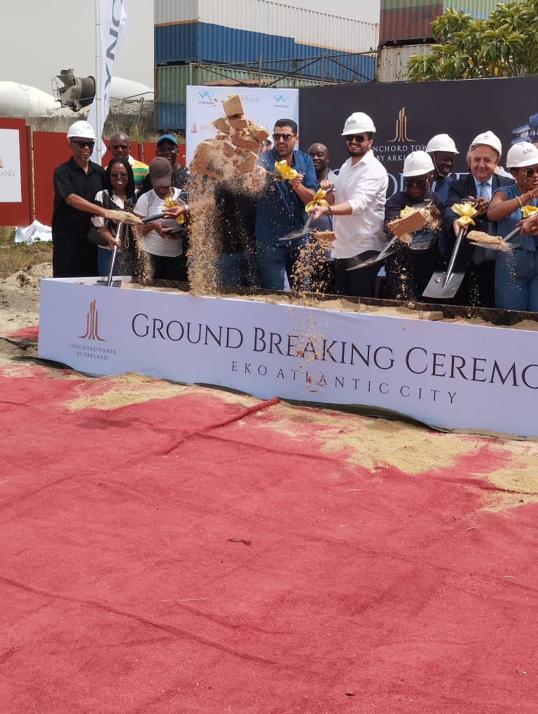Groundbreaking action moment in front of the event signage.